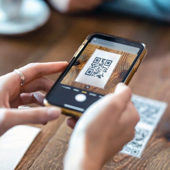 Close up of young woman hands using the smart phone to scan the qr code to select food menu in the restaurant.