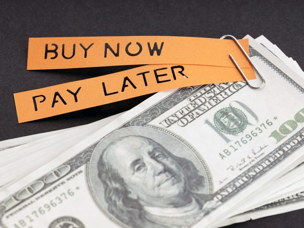 BNPL or Buy Now Pay Later concept. Dollar bills and label with message on black background