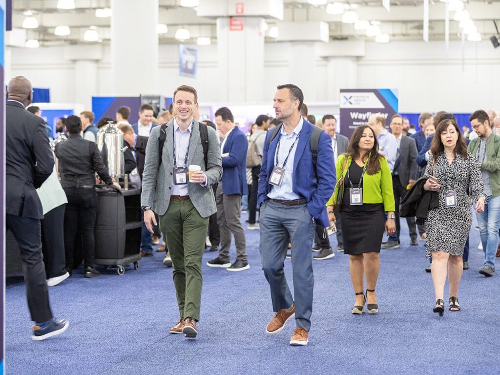 The expo hall was bustling at Fintech Nexus USA 2023 at the Javits Center. People can be seen walking on the blue carpet from the expo hall to the keynote stage.