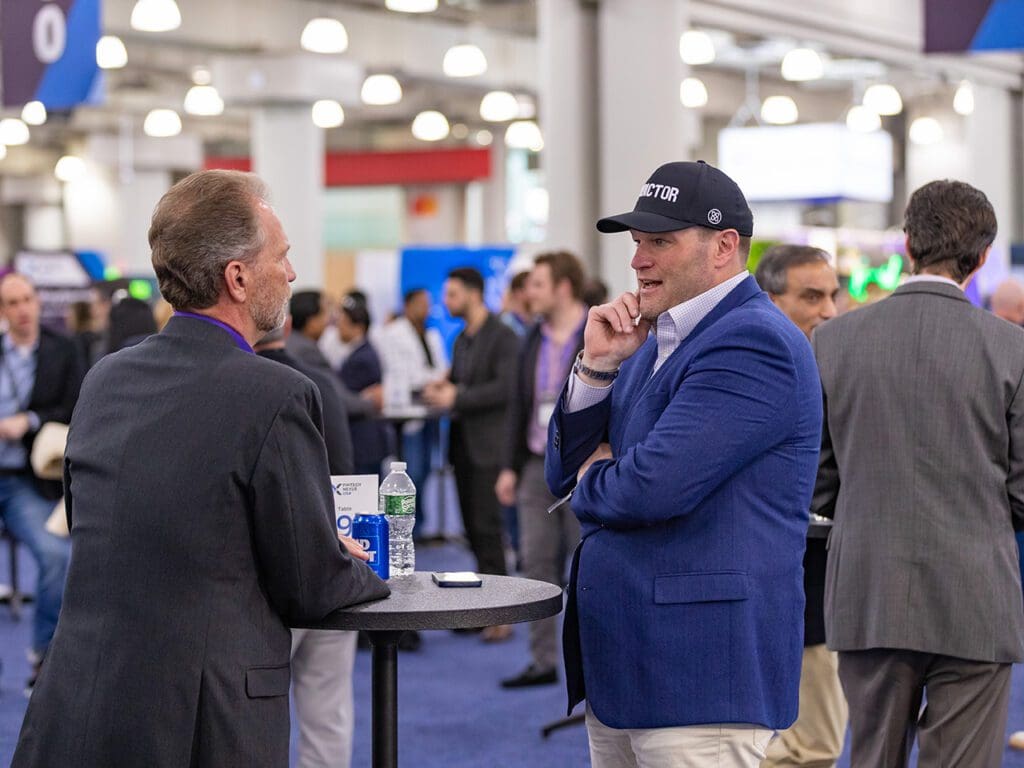 Two attendees talk at a table at the networking area at Fintech Nexus USA 2023.