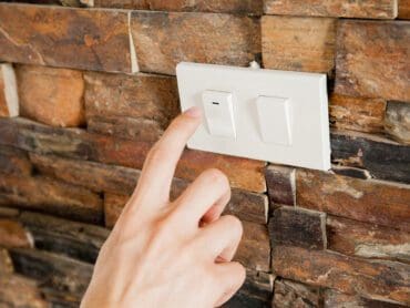 Human finger turning off the light switch - green earth and energy saving concept